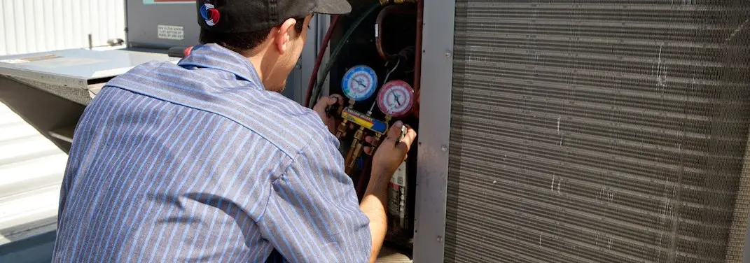 HVAC technician servicing a condenser unit in Hollis