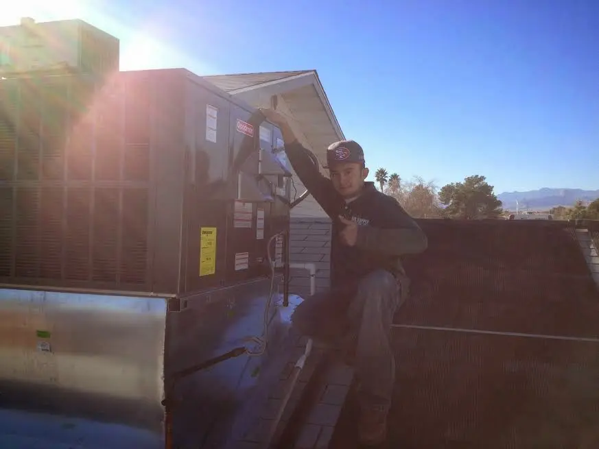 HVAC technician performing AC Tune-Up on a rooftop unit in Hollis